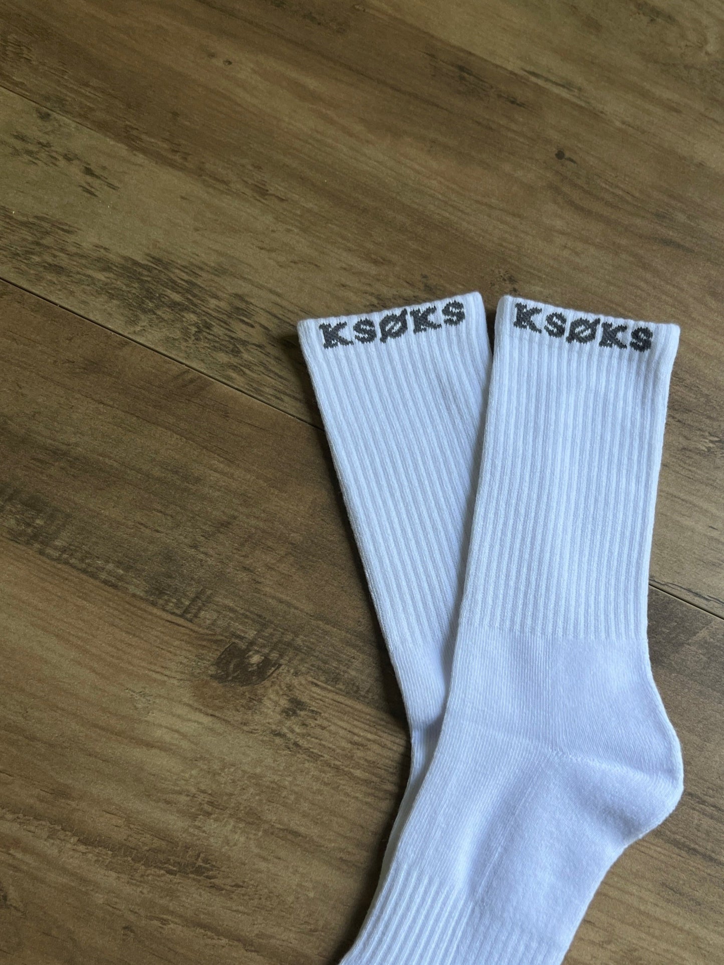 White socks with 'K-Swiss' branding on a wooden surface