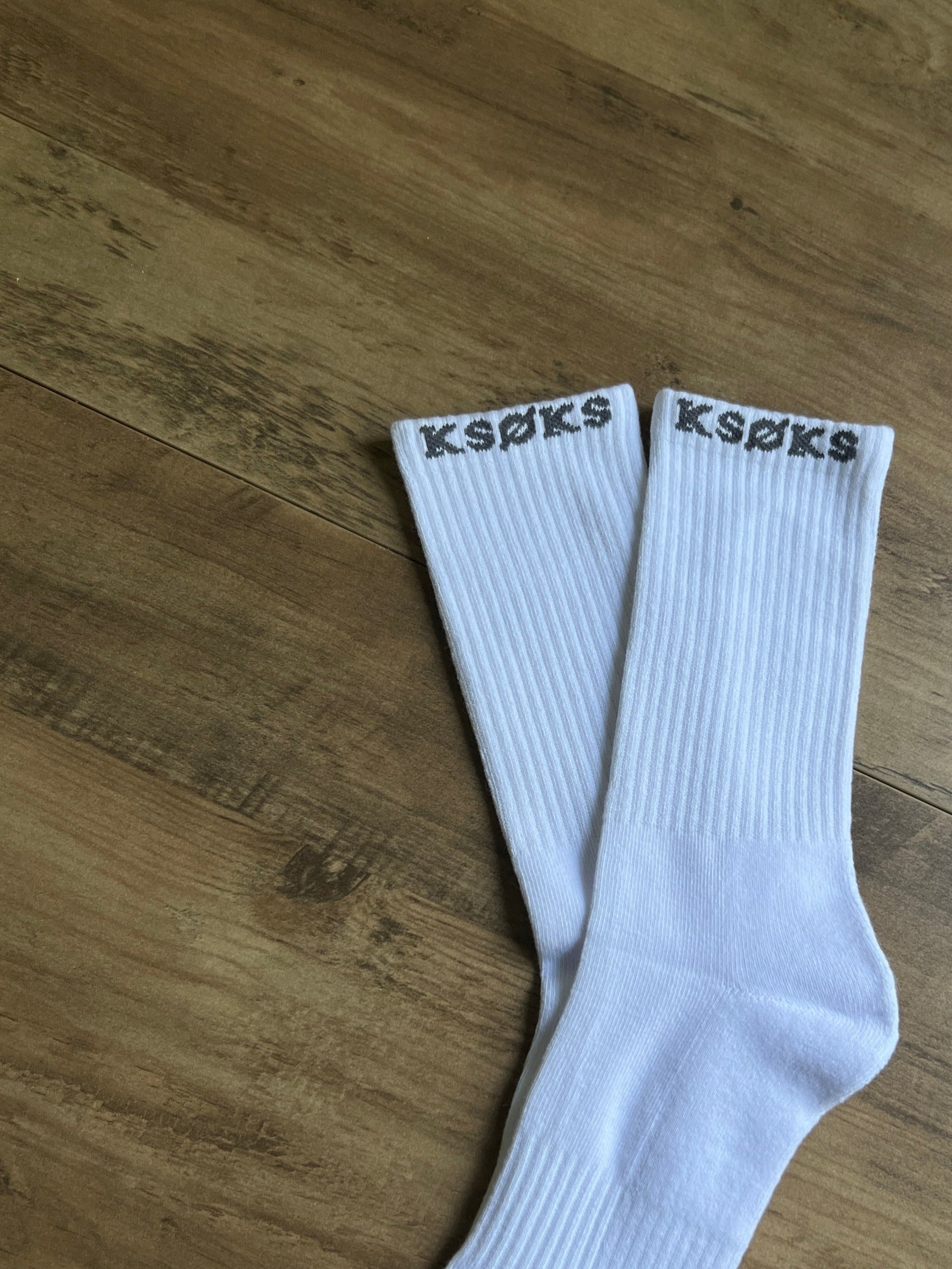 White socks with 'K-Swiss' branding on a wooden surface