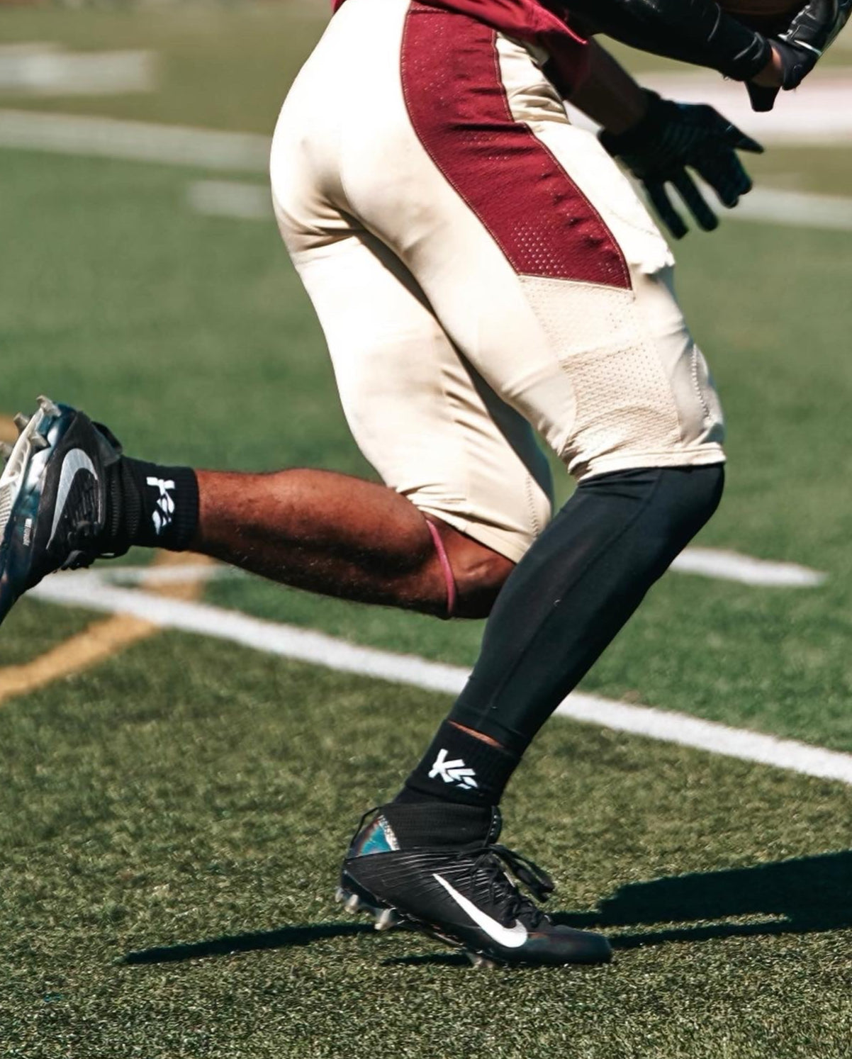 Football player in action on a field, wearing a red and white uniform with black cleats.