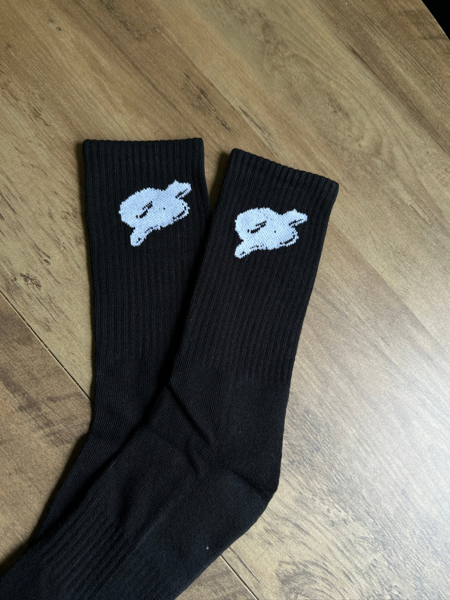 Black socks with white bunny designs on a wooden floor