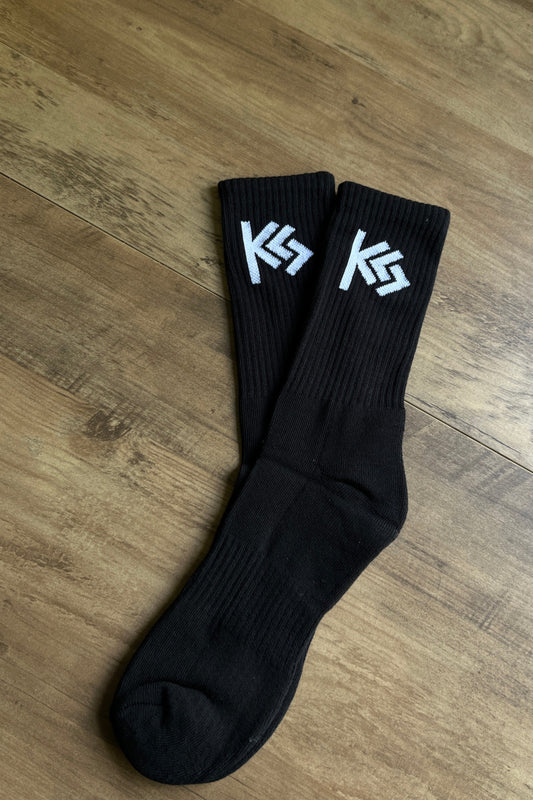 Black socks with white logo on a wooden table