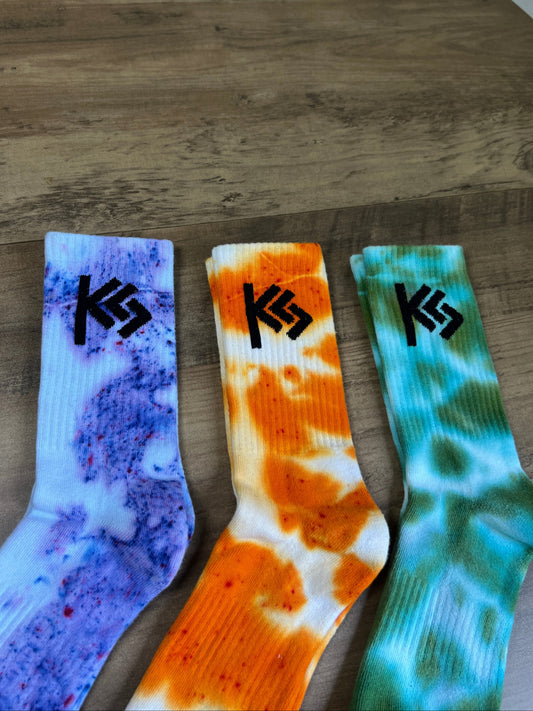 3 socks with different patterns and colors on a wooden surface